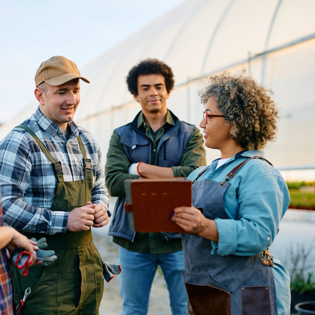 Group of workers cooperating while using touchpad at garden center.